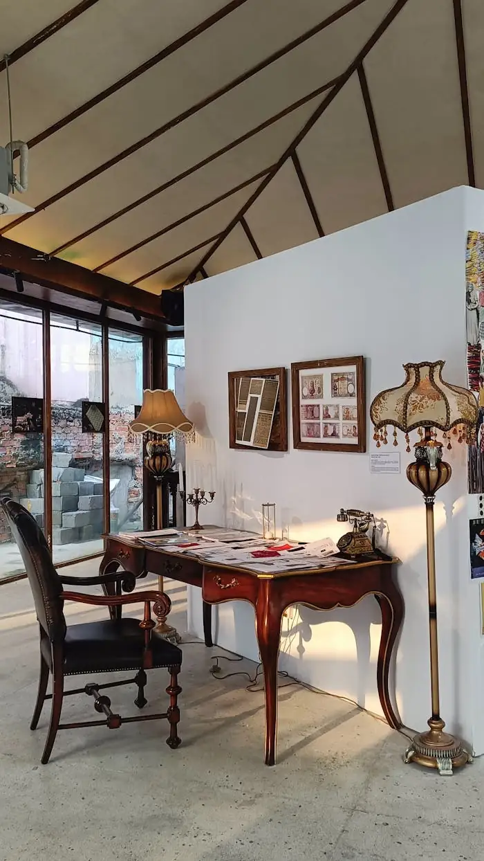 Et si votre logement devenait une galerie d’art ? A vintage workspace featuring a wooden desk, antique chair, and classic decor illuminated by natural sunlight.