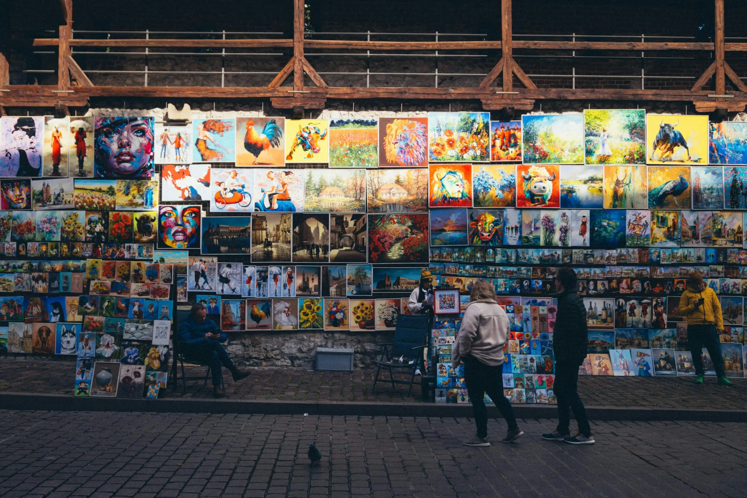 Quand la ville devient galerie : une nouvelle manière de vivre l’art Colorful paintings displayed on a street stall, attracting urban passersby.