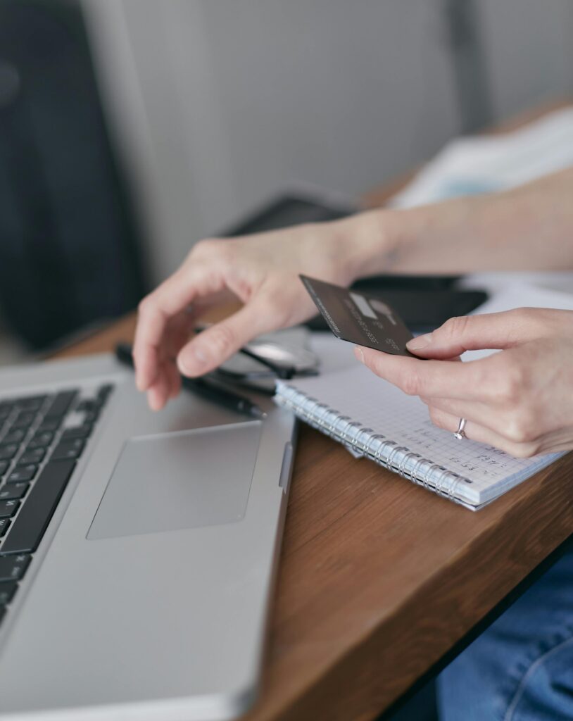 Close-up of hands holding credit card, shopping online using laptop.
